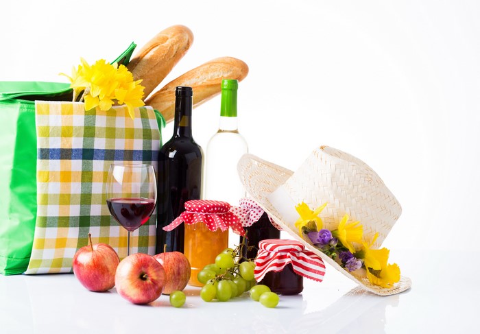 Picnic still life with wine, bread, jam, fruit, and hat