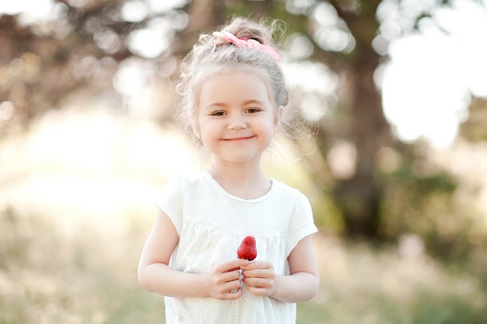 Little girl holding a strawberry