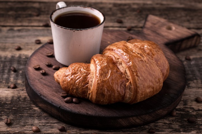 Croissant and Coffee Mug on Wooden Board
