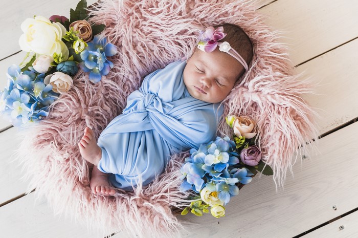 Newborn baby sleeping in a basket with flowers