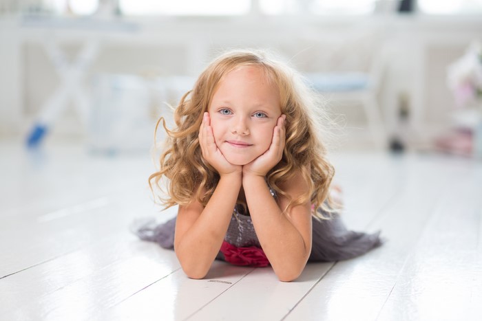 Young girl with blonde curly hair lying on the floor