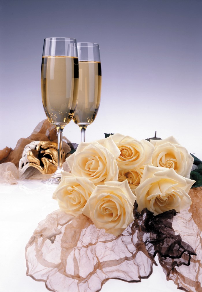 Champagne glasses with roses and a mask