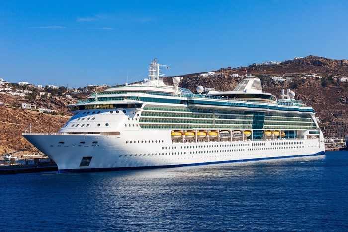 Cruise liner docked in a harbor with a town on a hill