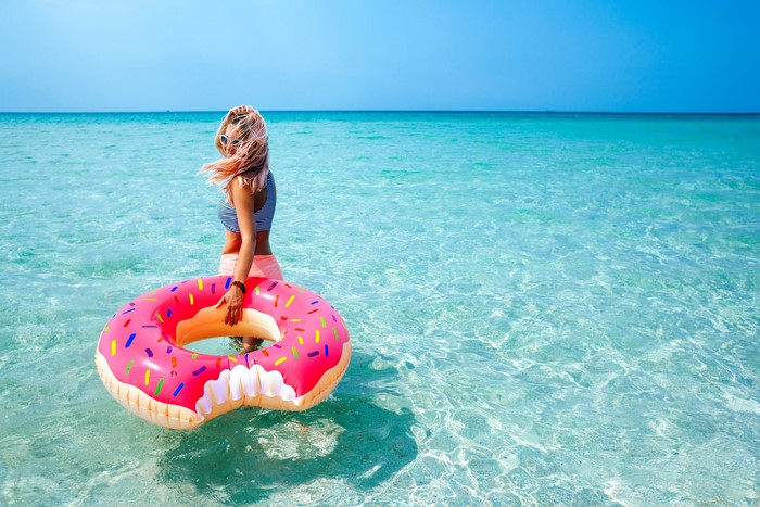 Blonde girl with donut float in the sea