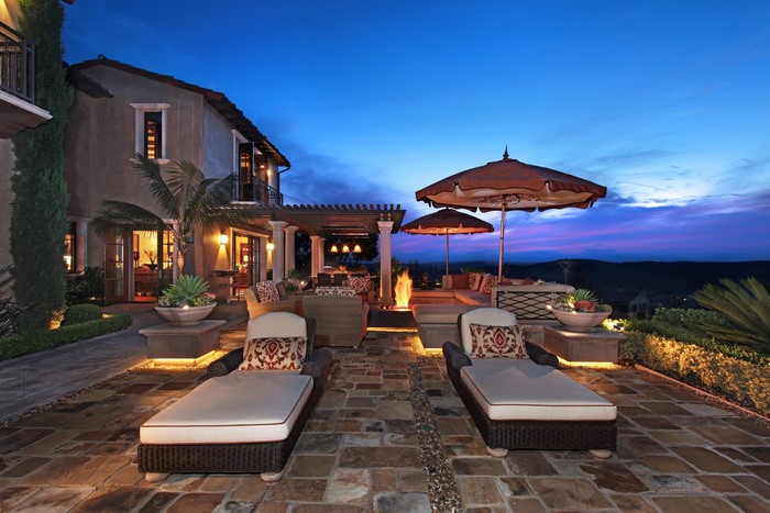 Luxury patio with lounge chairs and fire pit at dusk