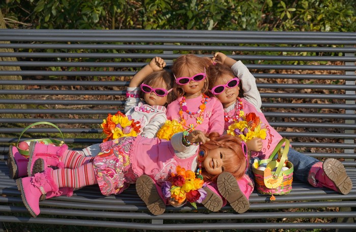 Four dolls with sunglasses on a bench