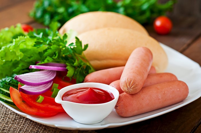 Hot dogs with buns, vegetables, and ketchup