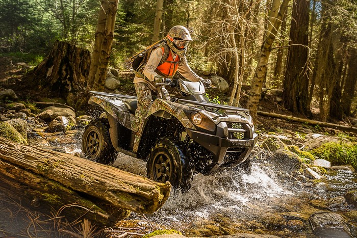Man Riding ATV Through Forest Stream