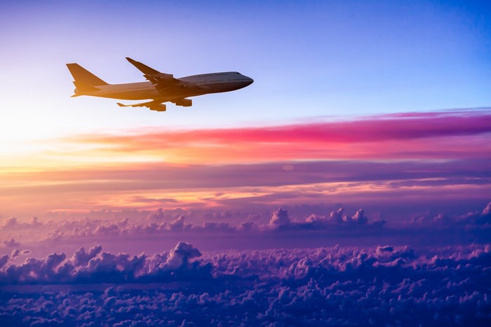 Airplane flying over clouds at sunset