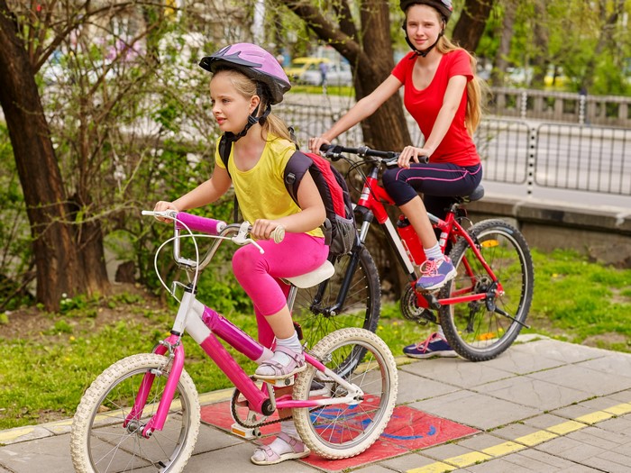 Two girls on bicycles wearing helmets
