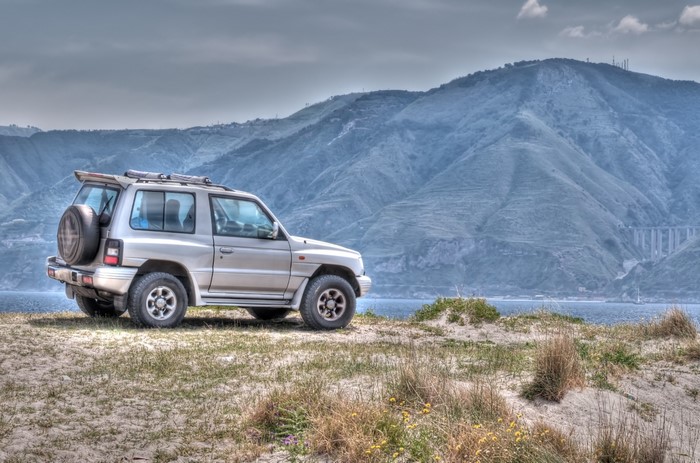 Silver SUV parked on a sandy hill overlooking the sea