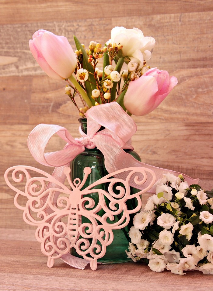 Pink tulips and white flowers in a green vase with a butterfly decoration