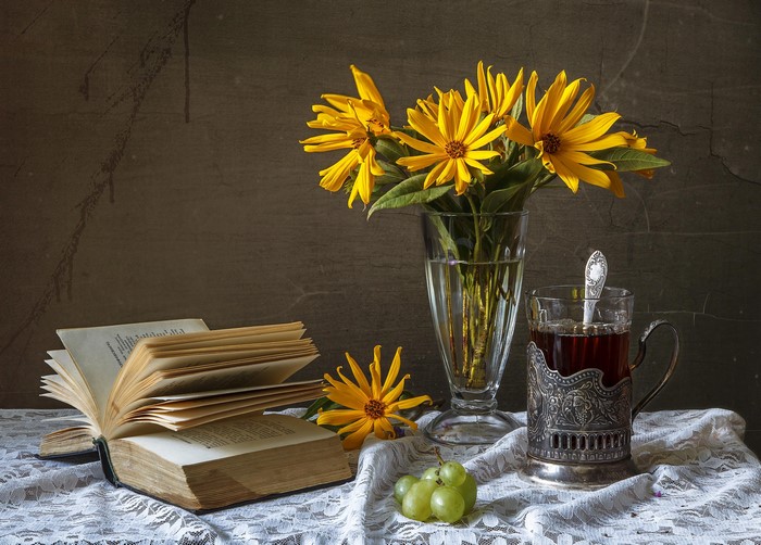 Still-life with yellow flowers, book, tea, and grapes