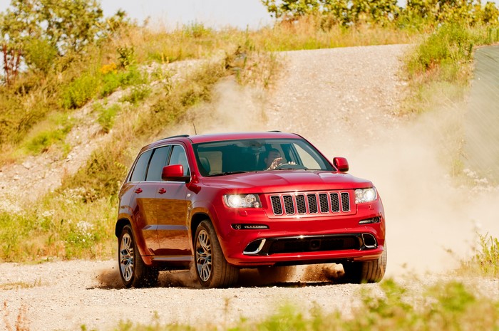 Red Jeep Grand Cherokee driving on a dirt road