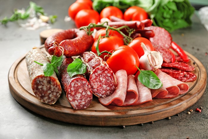 Assortment of Sausages and Tomatoes on a Cutting Board