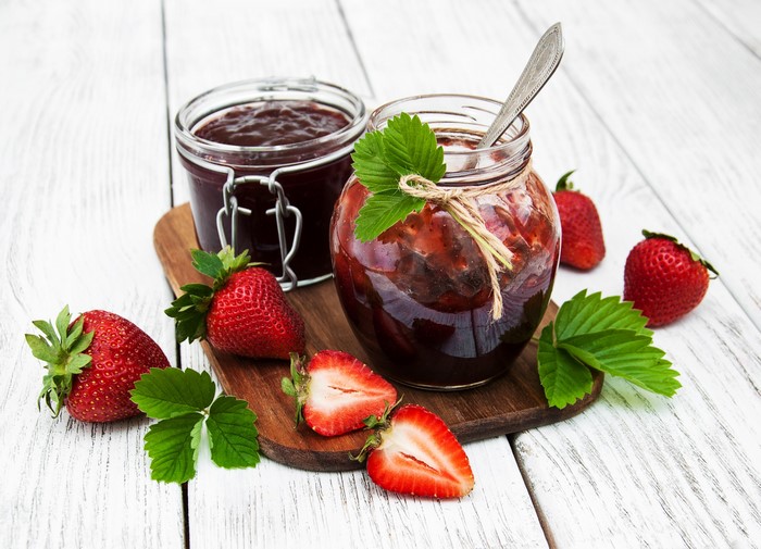 Strawberry jam in jars with fresh strawberries on wooden planks