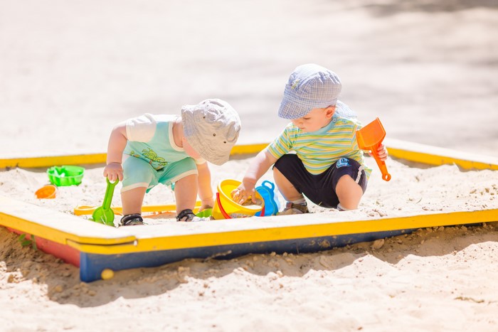 Two Boys Playing in a Sandbox with Toys