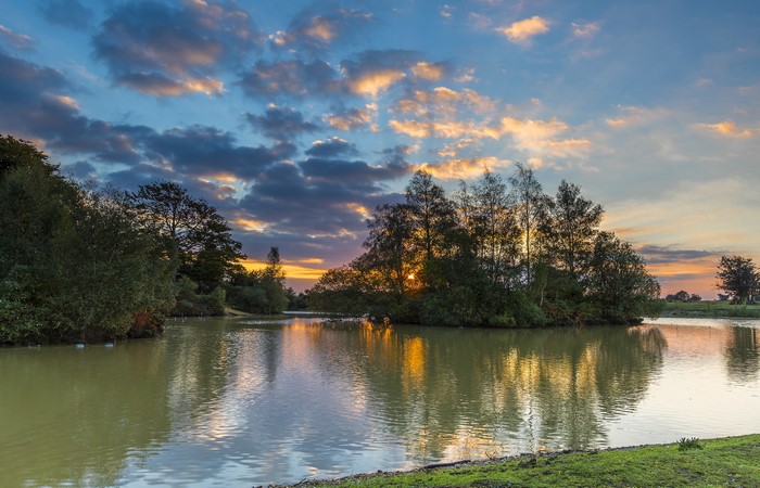 Sunset over a lake with trees and clouds in Fritham, England