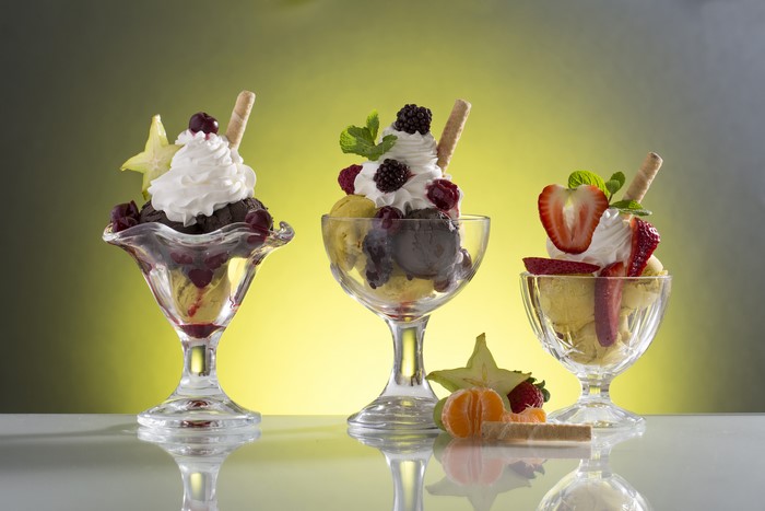 Three ice cream sundaes with fruits and whipped cream