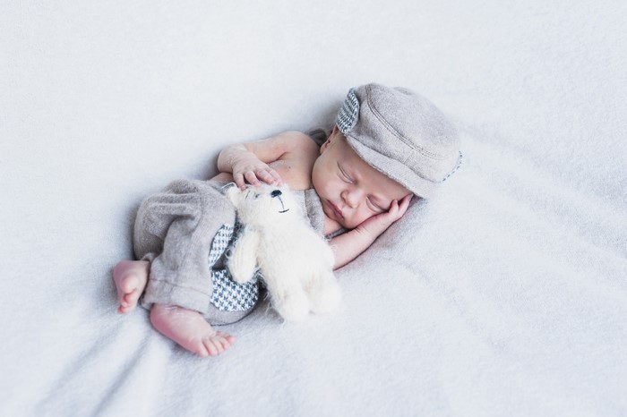 Baby sleeping with teddy bear and hat
