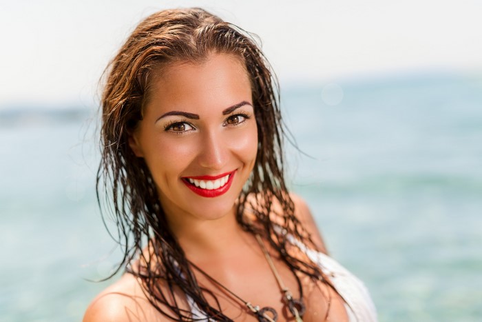 Woman with wet brown hair smiling at the beach