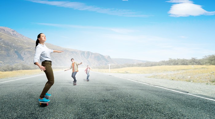 People skateboarding on a road with mountains