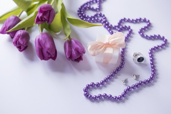 Purple tulips, gift box, and jewelry on a light background
