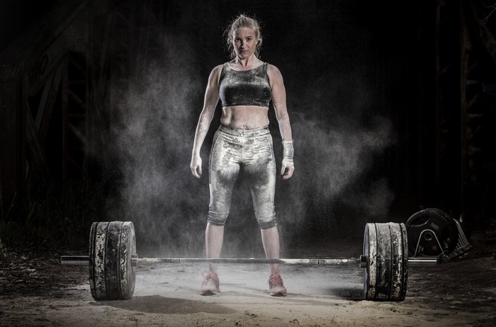 Woman covered in chalk with barbell
