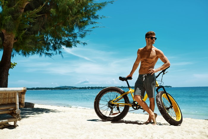 Man with sunglasses and bicycle on beach