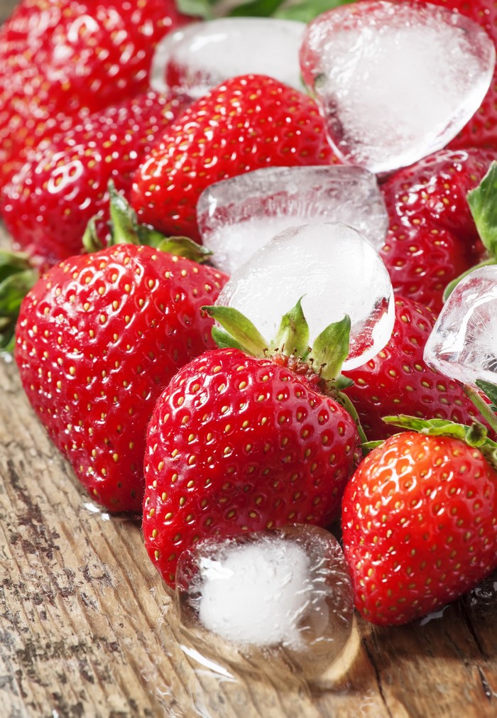 Strawberries and ice cubes on wood