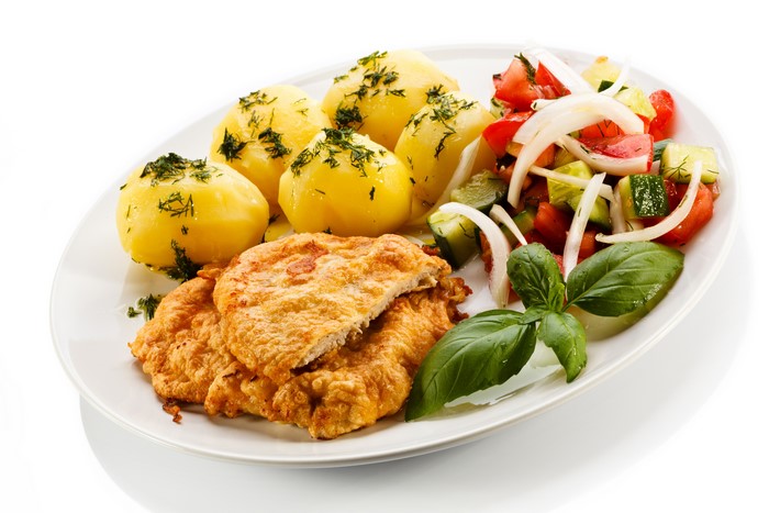 Fried meat with potatoes and salad on a white plate