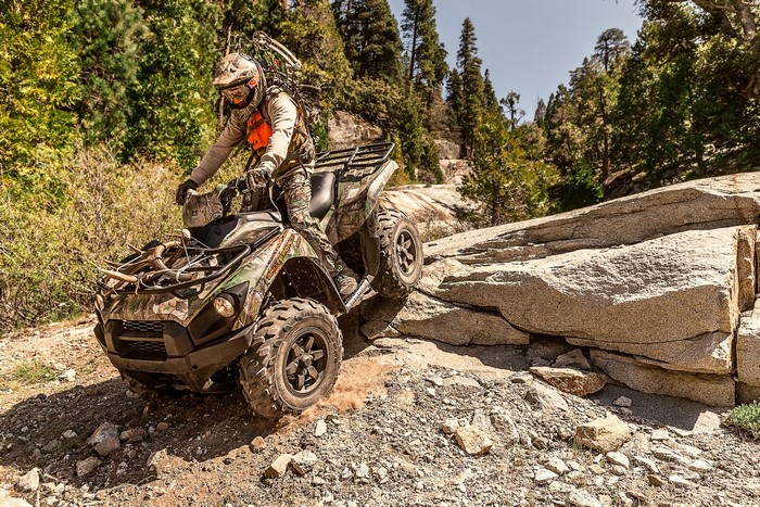 Man riding a camouflage ATV on a rocky trail