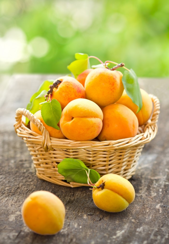Apricots in a wicker basket on a wooden table