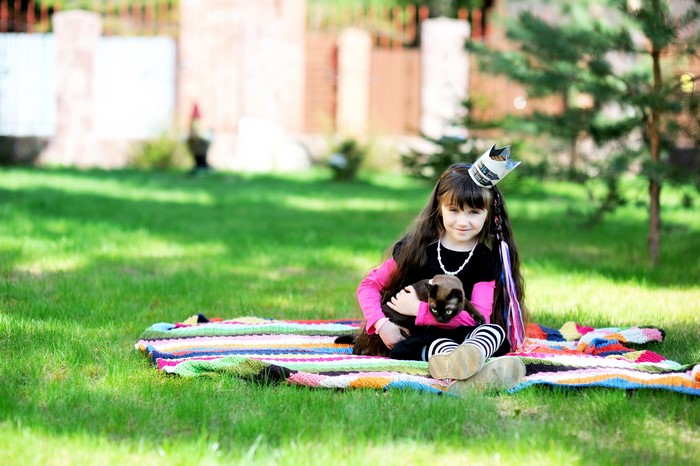 Girl with crown holding a kitten on a blanket