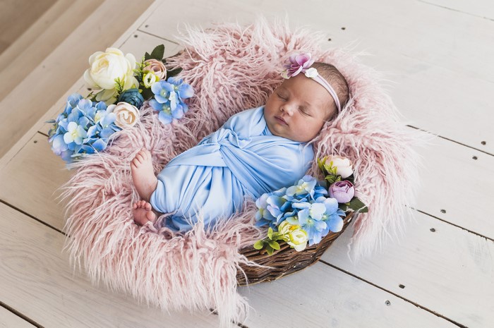 Newborn baby sleeping in a wicker basket with flowers