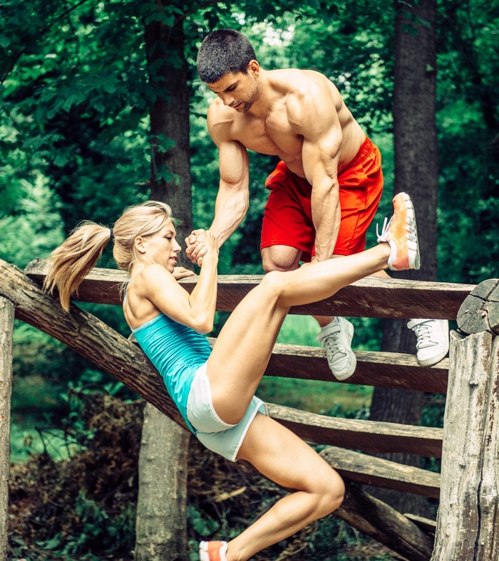 Man and woman doing fitness workout on wooden structure outdoors