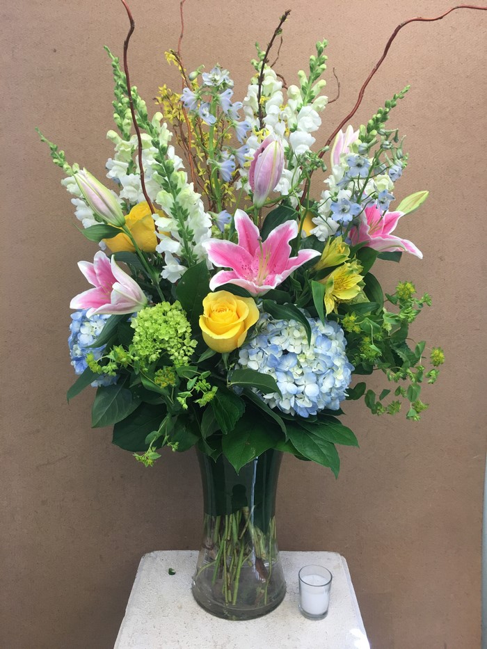 Pink lilies, yellow roses, and blue hydrangeas in a vase