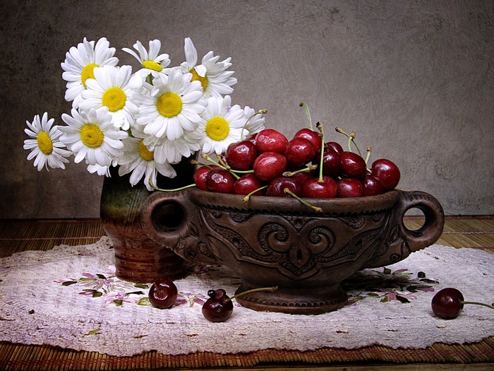 Still-life with camomiles and cherries in a vase