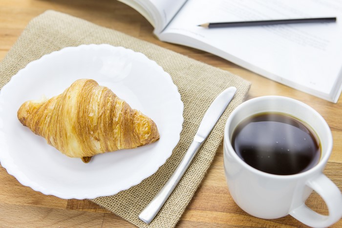 Croissant and coffee on a table with a book