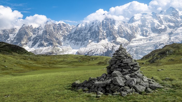 Stone cairn in front of snow-capped Alps mountains