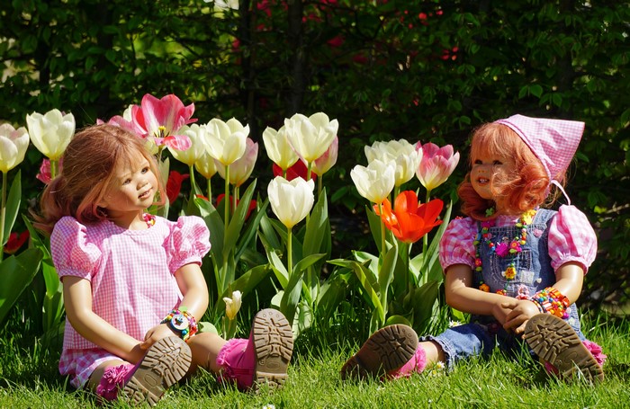Two dolls sitting in front of tulips in Grugapark Essen