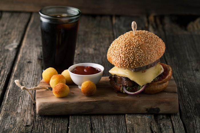 Hamburger with fries and soda on a cutting board