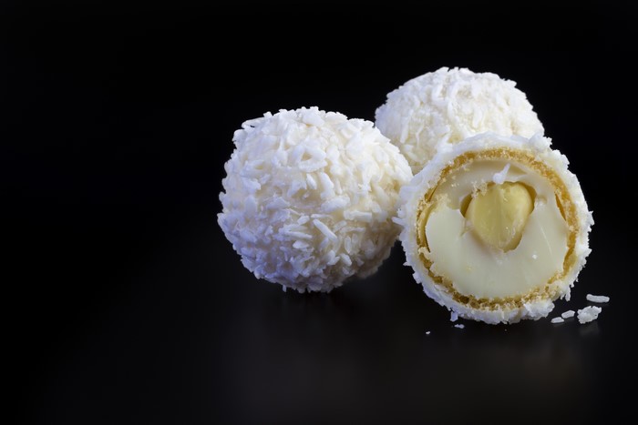Three white coconut candies with a black background