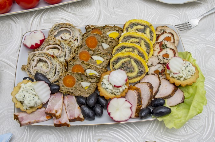 Appetizer platter with meat rolls, olives, and radishes
