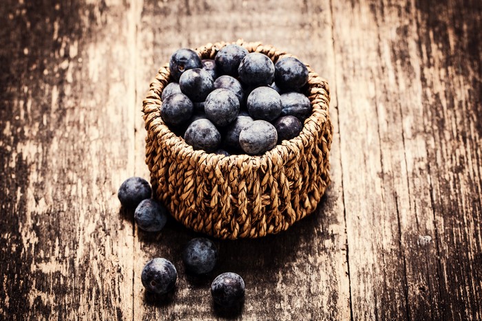 Blueberries in a wicker basket on wood planks
