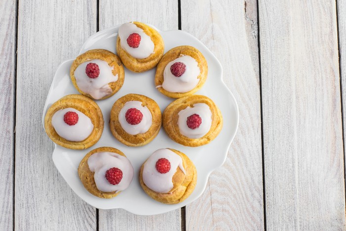 Little cakes with raspberry on a white plate