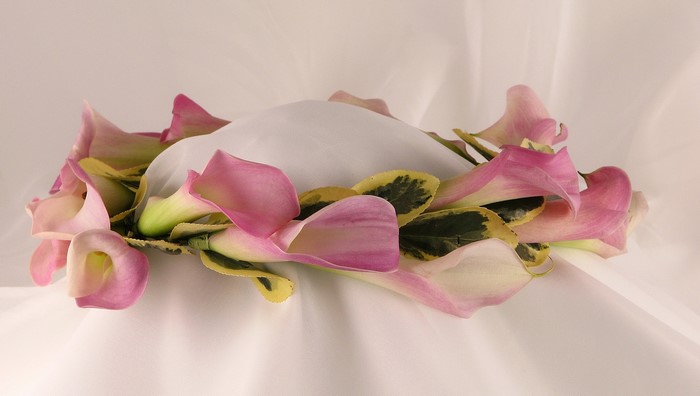 Pink and white calla lilies arranged around a white object