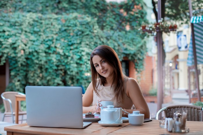 Woman with laptop and coffee at outdoor cafe