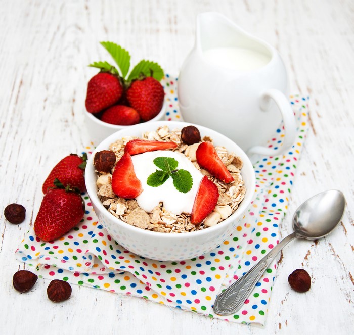 Bowl of muesli with strawberries, nuts, and milk