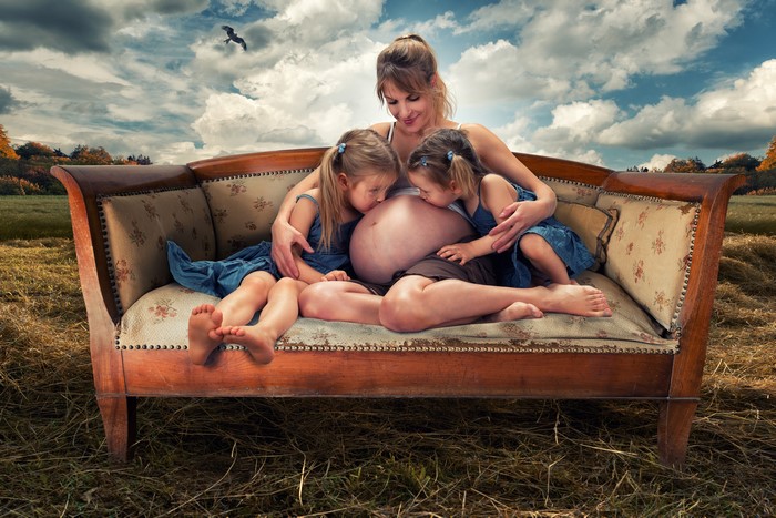 Pregnant Woman and Two Daughters on Sofa